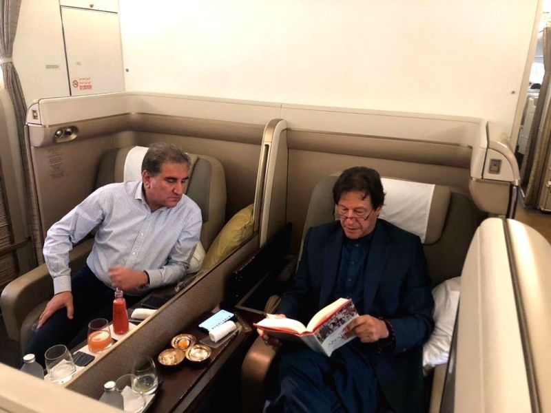 A photograph of Pakistan Prime Minister Imran Khan reading William Dalrymple's latest book 'The Anarchy' on his flight to Jeddah with Foreign Minister Shah Mahmood Qureshi peeking over from his seat has gone viral on social media.. (IANS Photo)